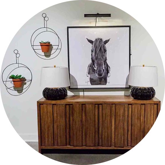 wooden console with a horse painting, lamps and hanging plants